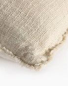 Beige woven outdoor pillow with fringe trim detail on corner.